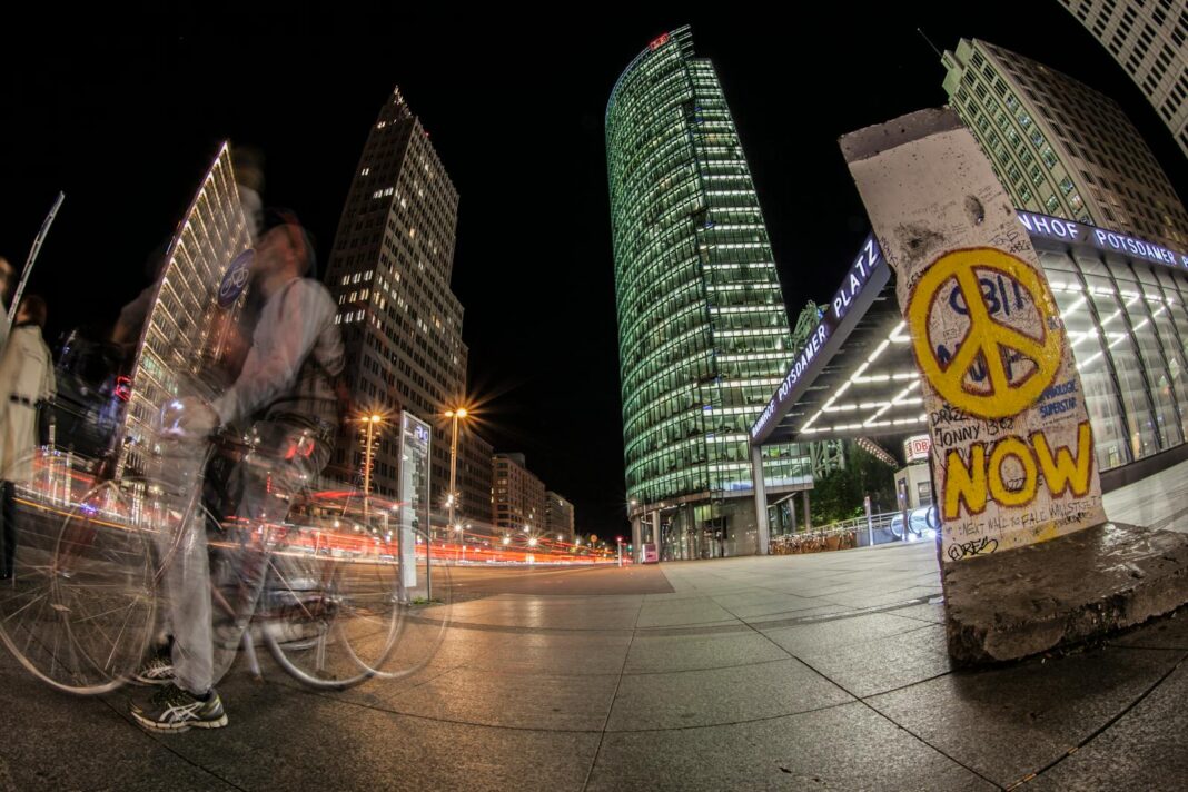 Dynamic night scene featuring architecture and light trails at Potsdamer Platz, Berlin, with graffiti in foreground.